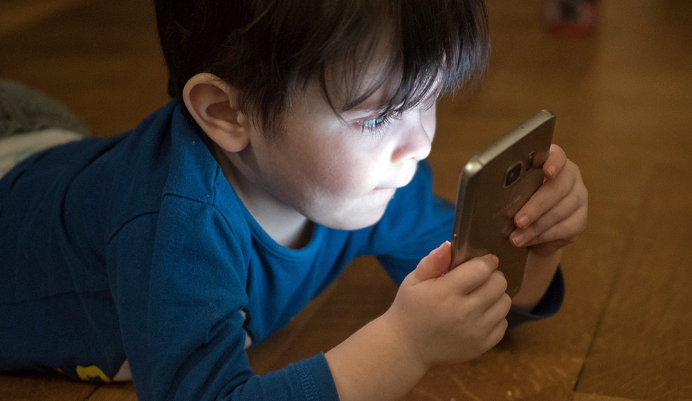 Enfant devant un téléphone pour illustrer un article sur les effets délétères des écrans sur les enfants